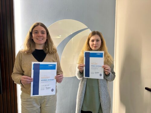 Alice and Millie holding their CIWEM membership certificates. Standing in front of the MSA logo.